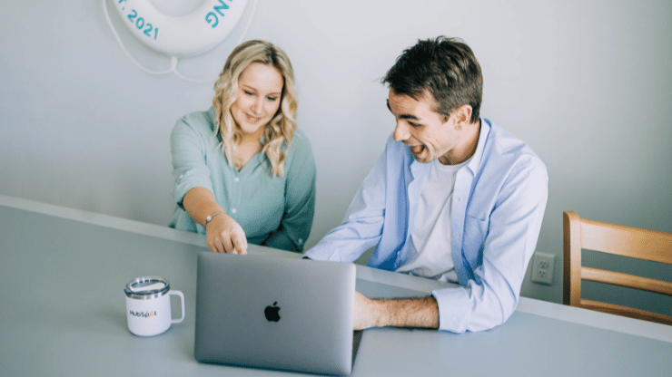 two coworkers at a table with a laptop