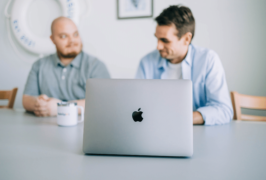 Two Men at a Table with a Laptop